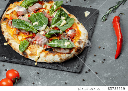 Meat Italian pizza with roast beef, steak slices, melted cheese, with olive slices and cheddar cheese. Close up, macro. Pizza time concept Meat Italian pizza with roast beef, steak slices, melted cheese, with olive slices and cheddar cheese. Close up, macro. Pizza time concept 85782339