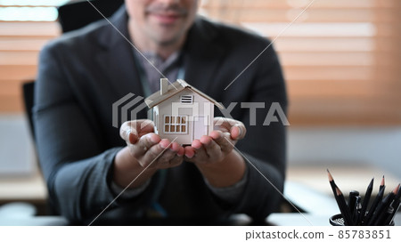 Real estate agent holding small house model. Mortgage and real estate investment concept. Real estate agent holding small house model. Mortgage and real estate investment concept. 85783851