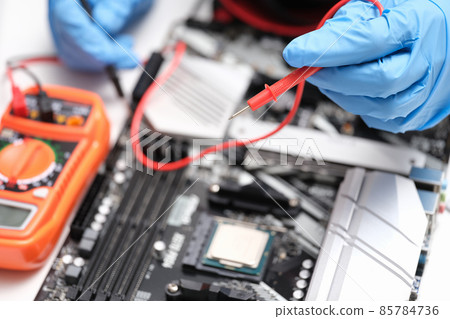 Hands with a multimeter to check electronic equipment 85784736