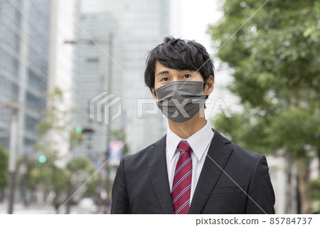 Young businessman in a gray non-woven mask 85784737