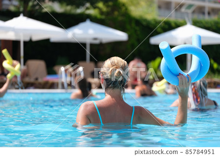 Woman in the pool doing exercises in aquafitness, back view Woman in the pool doing exercises in aquafitness, back view 85784951
