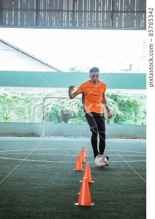 Asian male futsal players practice dribbling with obstacles 85785342