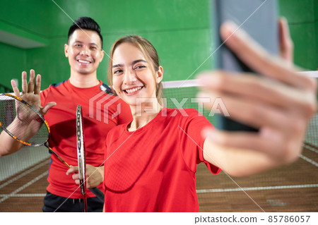 Male and female badminton players smiling while taking a selfie 85786057
