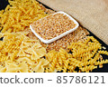 some dry wheat and different shapes of pasta standing on black background,close-up of macaroni and wheat together, 85786121
