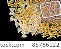 some dry wheat and different shapes of pasta standing on black background,close-up of macaroni and wheat together, 85786122