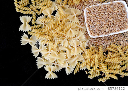 some dry wheat and different shapes of pasta standing on black background,close-up of macaroni and wheat together, some dry wheat and different shapes of pasta standing on black background,close-up of macaroni and wheat together, 85786122