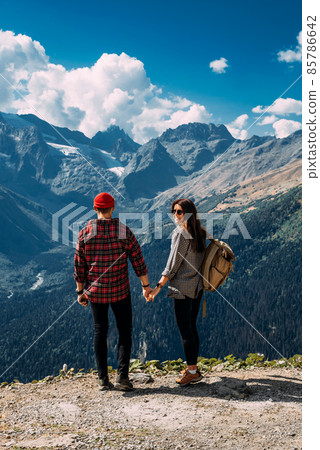 A couple in love on a rock admires the beautiful views. A man and a woman on a rock. A couple in love travels. A man and a woman in the Caucasus mountains. Couple traveling through the mountains 85786642