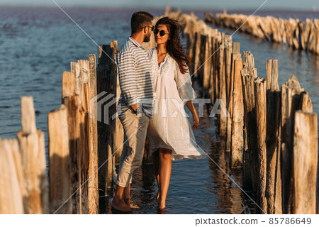 A couple in love on the seashore. A happy couple on a honeymoon by the sea. A beautiful couple on the coast. The honeymoon. Wedding trip. Copy space A couple in love on the seashore. A happy couple on a honeymoon by the sea. A beautiful couple on the coast. The honeymoon. Wedding trip. Copy space 85786649