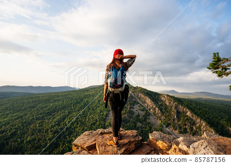 Traveler on the background of the mountain, rear view. A woman is traveling in Bashkiria, Russia. Mountain tourism in Russia. Walking tour of the mountains of Bashkiria, Aigir. Copy space Traveler on the background of the mountain, rear view. A woman is traveling in Bashkiria, Russia. Mountain tourism in Russia. Walking tour of the mountains of Bashkiria, Aigir. Copy space 85787156
