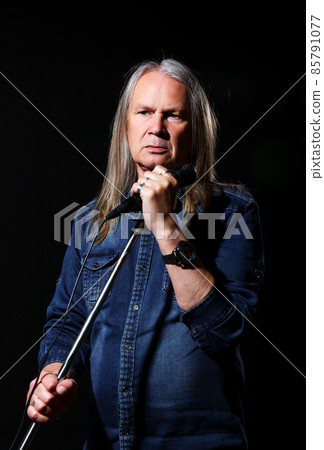 elderly man with long gray hair sings into a microphone elderly man with long gray hair sings into a microphone 85791077