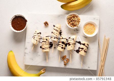 Cooking homemade banana lollipops with different sprinkles on white. Cooking homemade banana lollipops with different sprinkles on white. 85791348