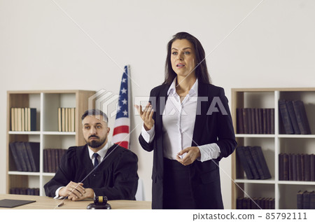 Female lawyer or defense attorney making passionate convincing speech defending her client. Young woman who represents person in lawsuit or criminal prosecution speaking to audience during court trial 85792111