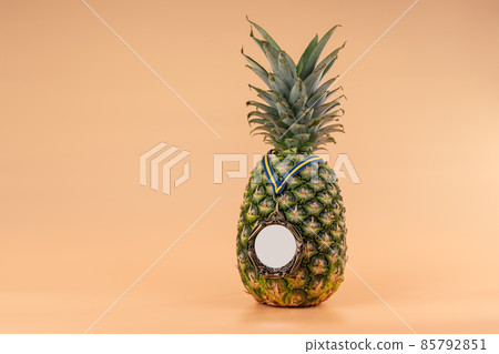 Interpretation of the pineapple fruit into a human image with a medal as a symbol of victory, success and strength. On a yellow background. 85792851