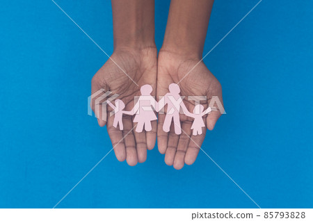 Hand holding family figure cutout top view. World health day Protection against domestic violence, healthcare and medical background. Foster care, homeless support and social distancing concept. 85793828
