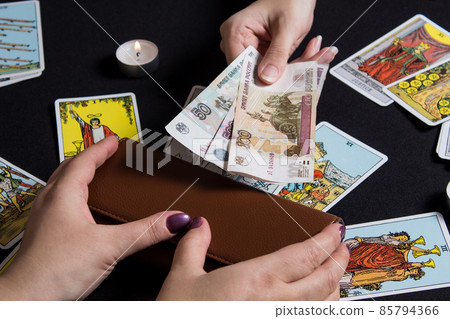 Moscow,Russia November 22.19. Hands holding cash Rubles on the background of wallet and Tarot cards. Payment for esoteric, magical and witchcraft services in Russia is made in national currency rubles 85794366