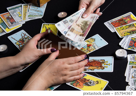 Moscow,Russia November 22.19. Hands holding cash Rubles on the background of wallet and Tarot cards. Payment for esoteric, magical and witchcraft services in Russia is made in national currency rubles 85794367