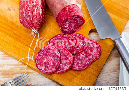 Sliced Iberian dry cured pork sausage salchichon on wooden background 85795285