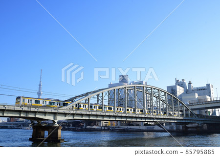 E231 series train that stops at each station on the Sobu Line that crosses Ryogoku Bridge with the Sky Tree in the background 85795885