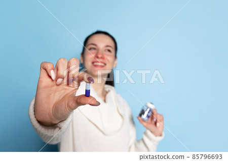 Portrait of young Caucasian girl feeling sick, sneezing isolated over blue background. Flu, cold, allergy Portrait of young Caucasian girl feeling sick, sneezing isolated over blue background. Flu, cold, allergy 85796693