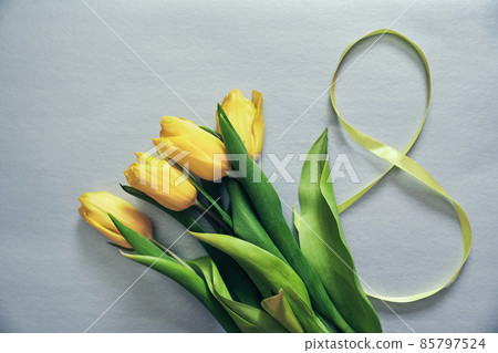 Five yellow fresh tulips on a grey background. Flowers with the number eight made of ribbon. Concept of holiday, March 8, International womans day. Card with copy space. Five yellow fresh tulips on a grey background. Flowers with the number eight made of ribbon. Concept of holiday, March 8, International womans day. Card with copy space. 85797524