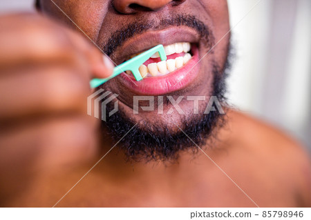 african american man cleaning his teeth with floss 85798946