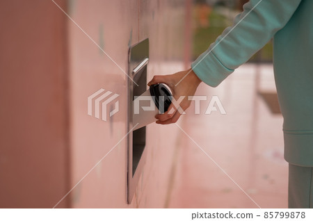 A woman throws a cup of coffee into a garbage manhole in the wall of a cafe. A woman throws a cup of coffee into a garbage manhole in the wall of a cafe. 85799878