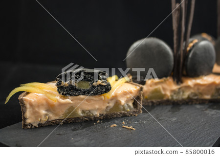 Orange chocolate tart sliced with black french macarons and persimmon Orange chocolate tart sliced with black french macarons and persimmon 85800016