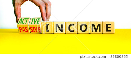 Passive or active income symbol. Businessman turns wooden cubes and changes words passive income to active income. Beautiful white background, copy space. Business, passive or active income concept. Passive or active income symbol. Businessman turns wooden cubes and changes words passive income to active income. Beautiful white background, copy space. Business, passive or active income concept. 85800865
