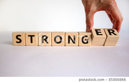 Strong or stronger symbol. Businessman turns wooden cubes, changes the word 'strong' to 'stronger'. Beautiful white background, copy space. Business and strong or stronger concept. 85800866