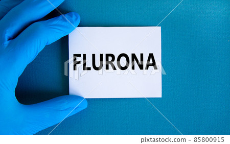 Covid-19 corona and flu flurona symbol. Hand in blue glove with white card. The concept word Flurona. Stethoscope. Medical and COVID-19 corona and flu flurona concept. Copy space. 85800915