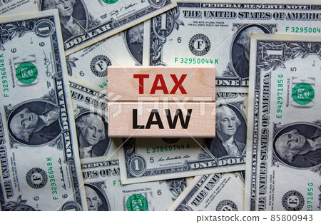 Tax law symbol. Concept words 'Tax law' on wooden blocks on a beautiful background from dollar bills. Business and tax law concept. 85800943