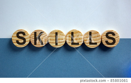 Wooden small circles with word 'skills' on blue and white background. Business concept, copy space. 85801081