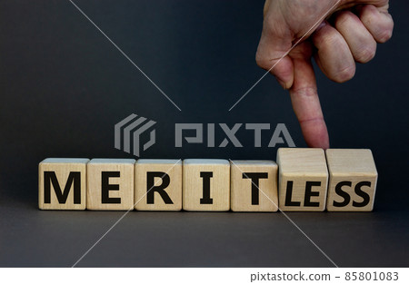 Merit or meritless symbol. Businessman turns wooden cubes and changes the word meritless to merit. Beautiful grey table, grey background. Business and merit or meritless concept. Copy space. Merit or meritless symbol. Businessman turns wooden cubes and changes the word meritless to merit. Beautiful grey table, grey background. Business and merit or meritless concept. Copy space. 85801083
