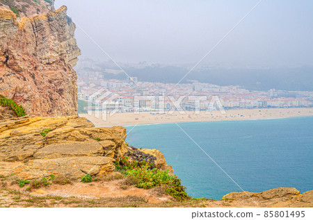 Aerial view of rocks and cliffs, azure turquoise water of Atlantic Ocean and sandy beach coastline Praia da Nazare Aerial view of rocks and cliffs, azure turquoise water of Atlantic Ocean and sandy beach coastline Praia da Nazare 85801495