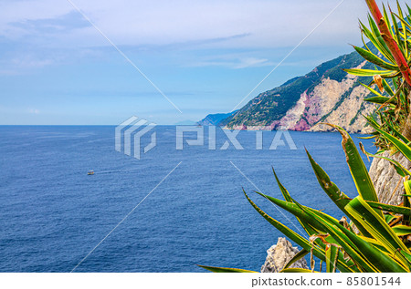 Grotta di Lord Byron with blue water, coast with rock cliff, yellow boat and blue sky near Portovenere town 85801544