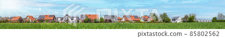 A housing estate with solar panels on the roof. Green field 85802562