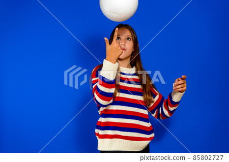 The girl is spinning the ball on her finger. The concept of relaxation, fitness and gymnastics. Isolated over blue background. 85802727