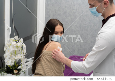 The COVID vaccine19. The doctor is getting ready to inject the vaccine into a teenager. A sterile doctor's office. Disinfects the chipping bowl. 85811920