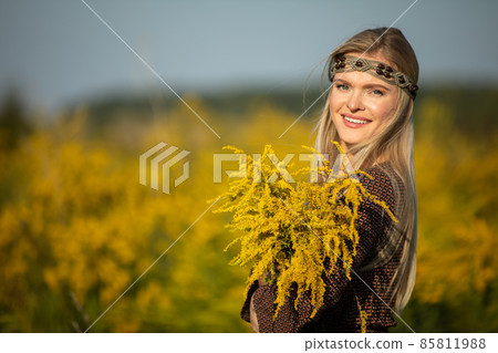 A young herbalist enjoys this year's crop of goldenrod herbs and watches the inflorescences. 85811988