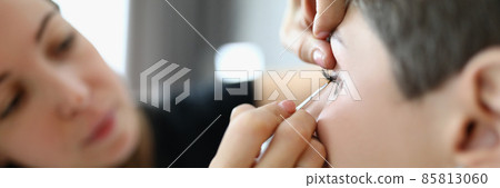 Woman stylist paints eyes of client close-up Woman stylist paints eyes of client close-up 85813060