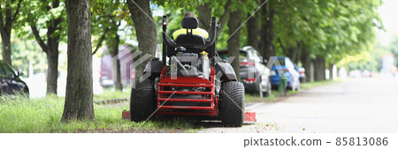 The lawn mower stands on sidewalk near the lawn 85813086