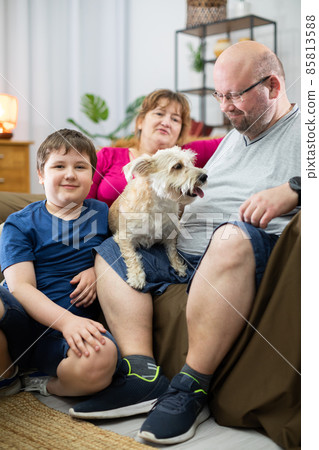 A happy and smiling family with a shaggy dog enjoy an afternoon of relaxation. A happy and smiling family with a shaggy dog enjoy an afternoon of relaxation. 85813588