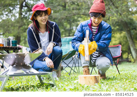 A woman chopping wood at a camp 85814525