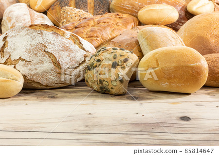 Many kinds and kinds of bread collected in one place on a wooden old shop counter as a decoration for a traditional bakery. View from above. Many kinds and kinds of bread collected in one place on a wooden old shop counter as a decoration for a traditional bakery. View from above. 85814647