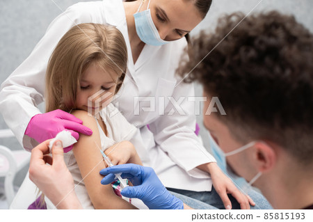 The doctor is getting ready to vaccinate a little girl. A young nurse sits next to the child to make the child feel safe. Preventive vaccine for young children. The doctor is getting ready to vaccinate a little girl. A young nurse sits next to the child to make the child feel safe. Preventive vaccine for young children. 85815193