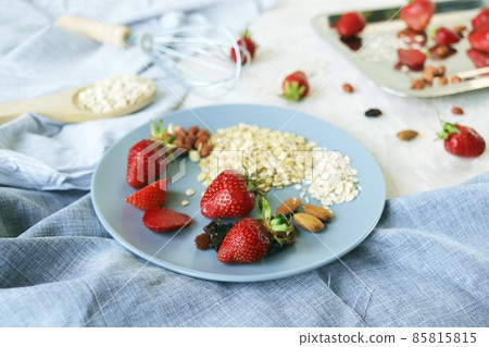 Healthy breakfast ingredients on the table, strawberries, oatmeal and nuts on a light background 85815815