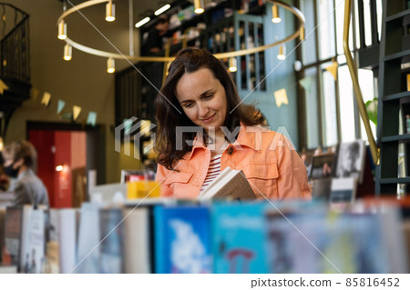 Young Pretty Caucasian Woman Choosing New Book in a Bookstore Young Pretty Caucasian Woman Choosing New Book in a Bookstore 85816452