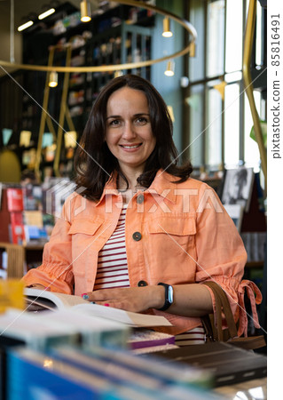 Portrait of Young Beautiful Female Customer Holding Book in a Bookstore Portrait of Young Beautiful Female Customer Holding Book in a Bookstore 85816491