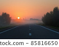 Empty Road Leading to Golden Sunrise on Foggy Morning 85816650