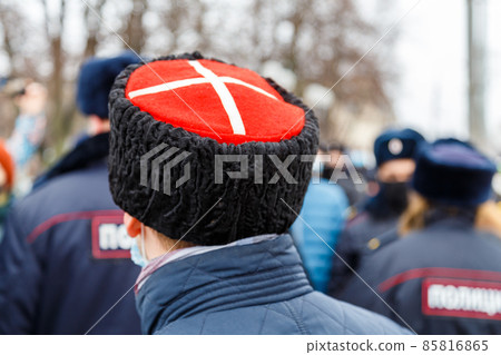 man in cossack hat with white cross on red watching blurry crowd of people man in cossack hat with white cross on red watching blurry crowd of people 85816865